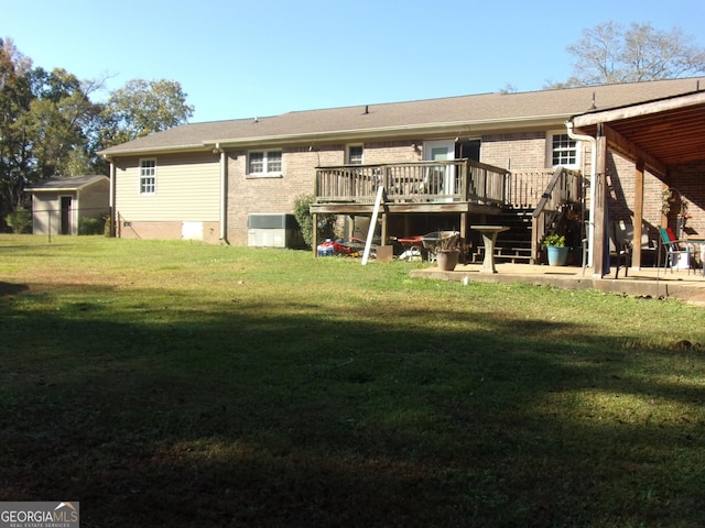 rear view of property featuring a deck, brick siding, and a lawn