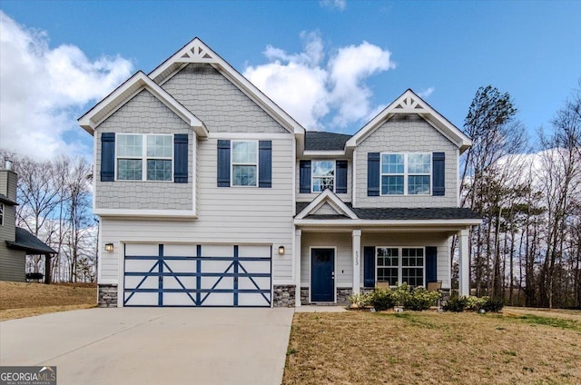 craftsman house with driveway, stone siding, a garage, and a front yard