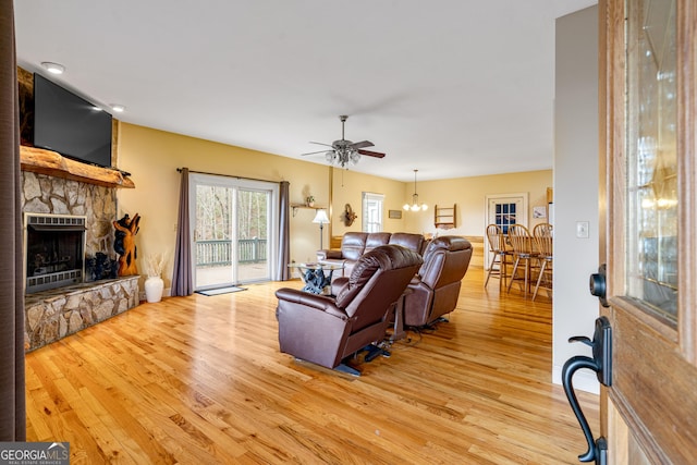 living area with light wood-type flooring, a fireplace, and a ceiling fan