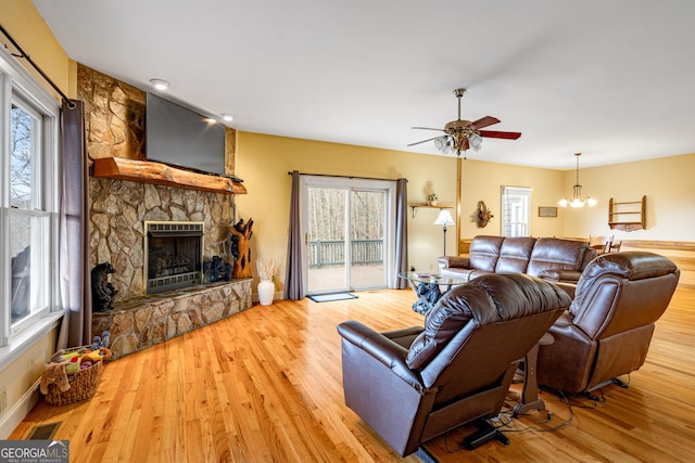 living room with ceiling fan, a fireplace, visible vents, and wood finished floors