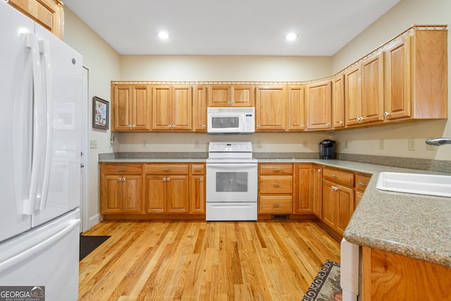 kitchen with white appliances, light stone counters, light wood-style floors, a sink, and recessed lighting