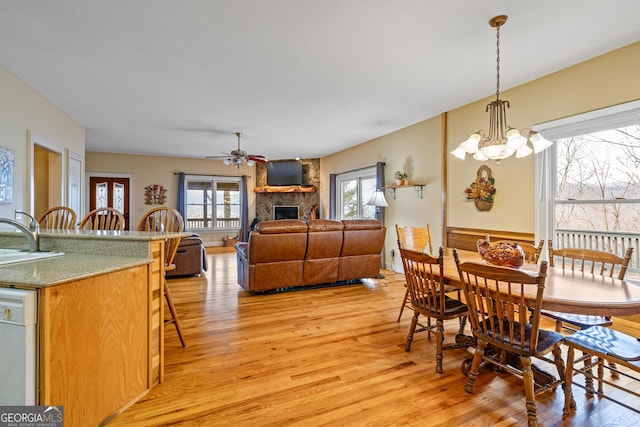 dining area featuring a stone fireplace, light wood-type flooring, and a wealth of natural light