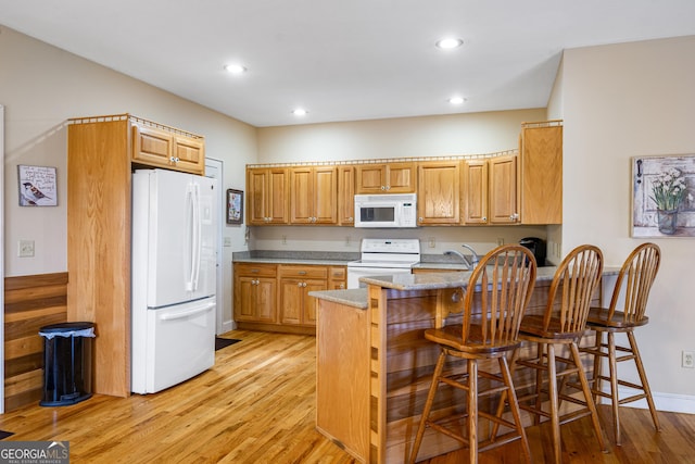 kitchen with a peninsula, white appliances, light wood-type flooring, and light stone counters