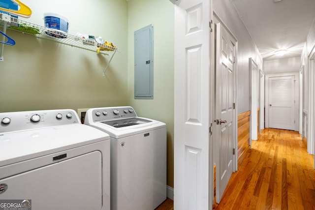 clothes washing area with laundry area, light wood-style flooring, electric panel, and separate washer and dryer