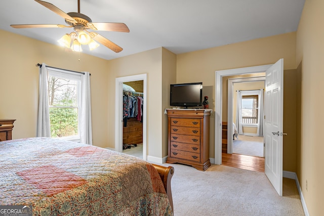 bedroom with baseboards, a spacious closet, multiple windows, and light colored carpet