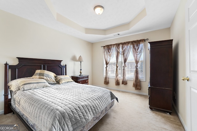 bedroom with light carpet, baseboards, visible vents, a tray ceiling, and a textured ceiling