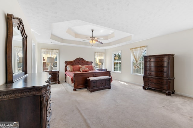 bedroom featuring a ceiling fan, a raised ceiling, light colored carpet, and baseboards