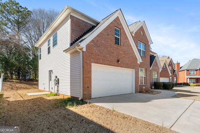 view of side of property featuring a garage, a residential view, concrete driveway, and brick siding