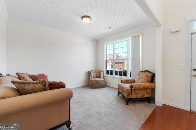 sitting room with baseboards, visible vents, and crown molding