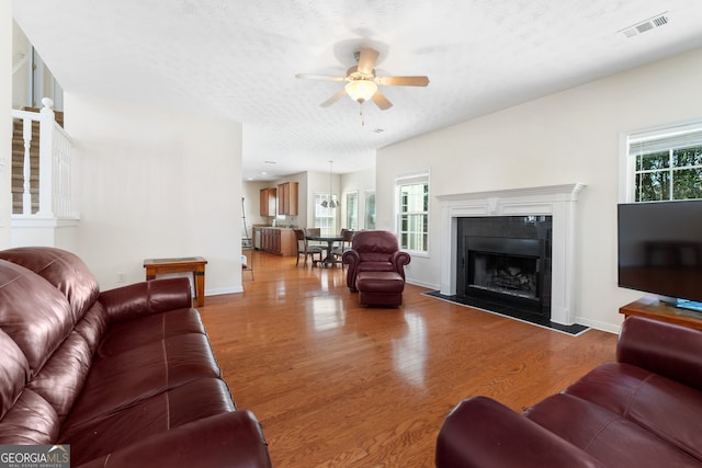 living area with plenty of natural light, visible vents, wood finished floors, and a tile fireplace