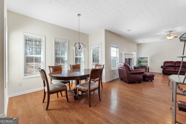 dining area featuring light wood finished floors, a fireplace, and a textured ceiling