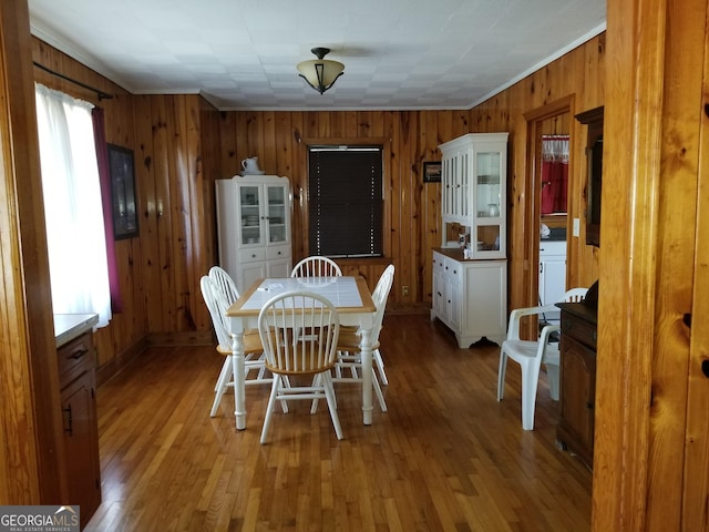 dining space with wooden walls and wood finished floors