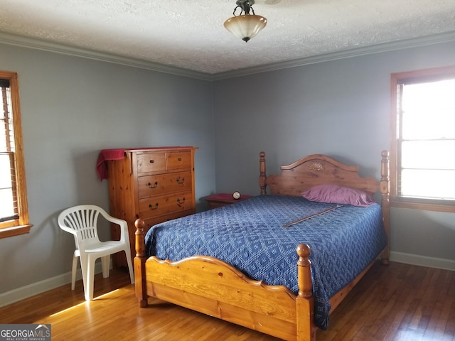 bedroom with ornamental molding, wood finished floors, and baseboards
