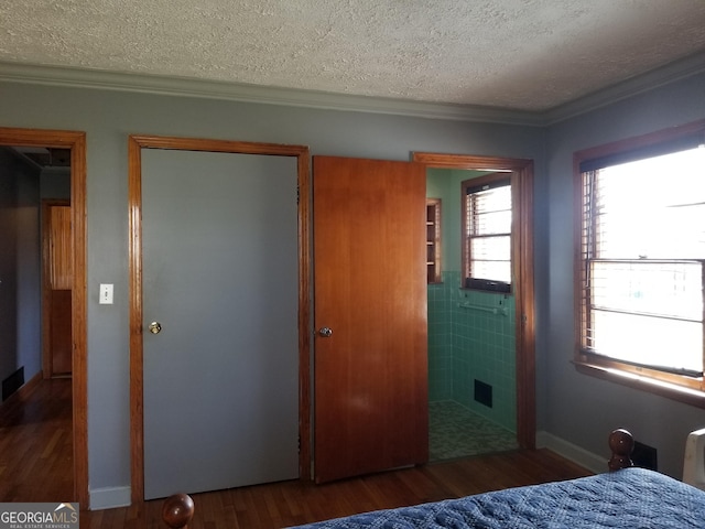 bedroom featuring visible vents, crown molding, a textured ceiling, and wood finished floors