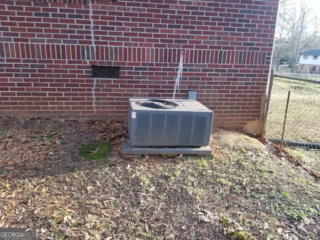 exterior details featuring central AC unit, fence, and brick siding
