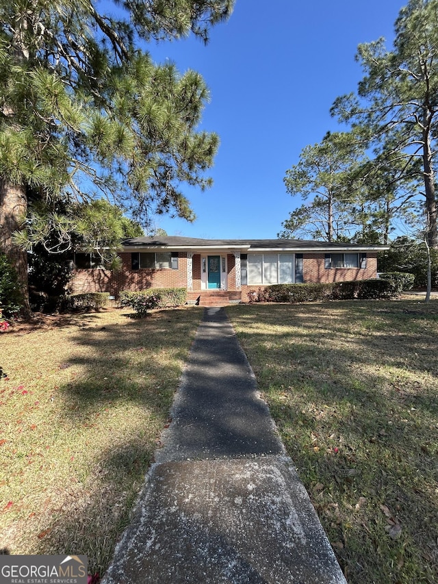 ranch-style home with a front yard and brick siding