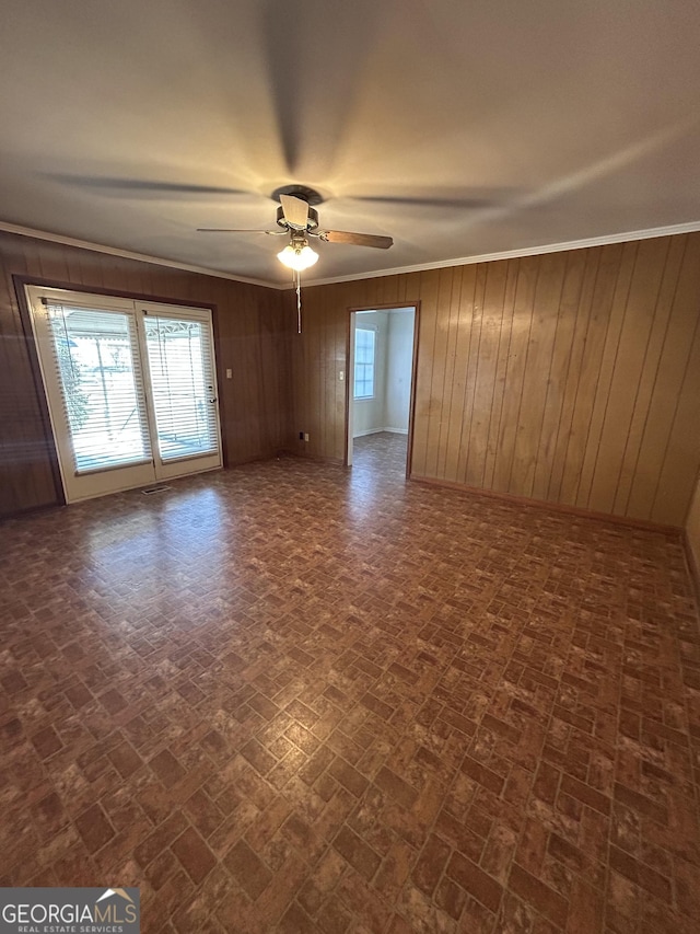 empty room with ornamental molding, plenty of natural light, brick patterned floor, and a ceiling fan