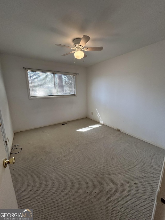 empty room with carpet, visible vents, and a ceiling fan