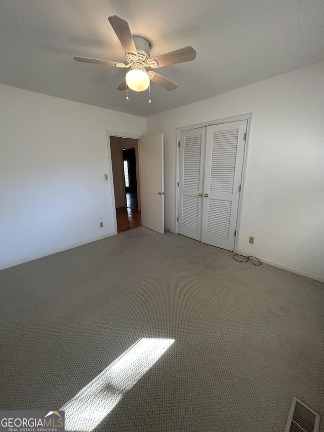unfurnished bedroom featuring light carpet, ceiling fan, visible vents, and a closet