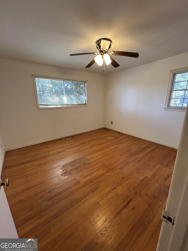 empty room with visible vents, ceiling fan, and wood finished floors