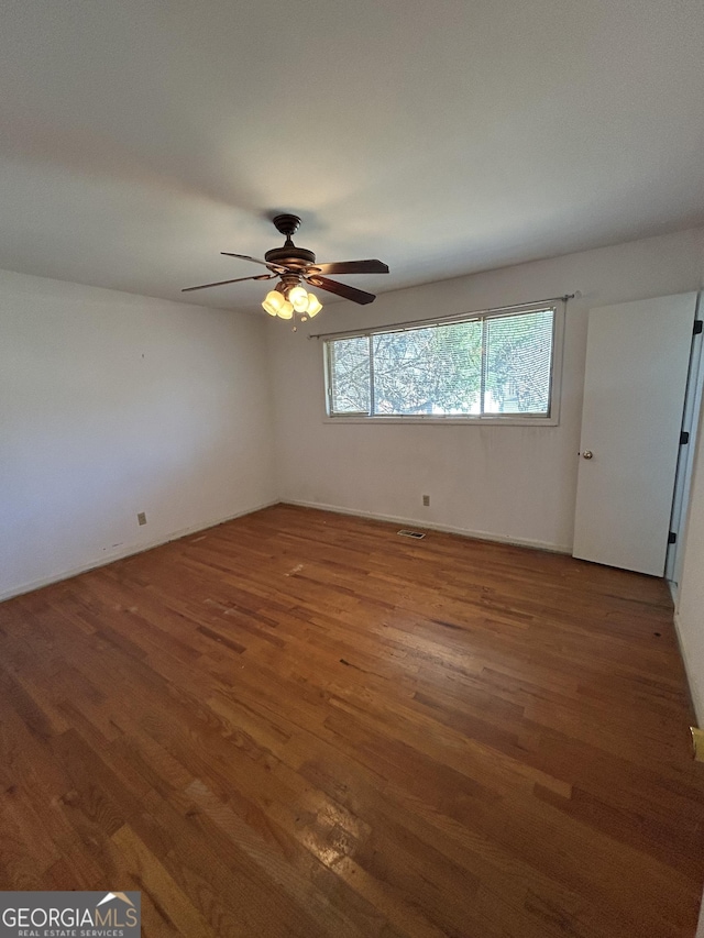 unfurnished room with a ceiling fan, visible vents, and wood finished floors