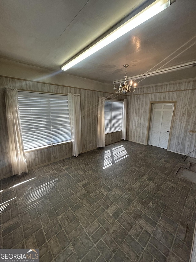 empty room with a notable chandelier and brick patterned floor