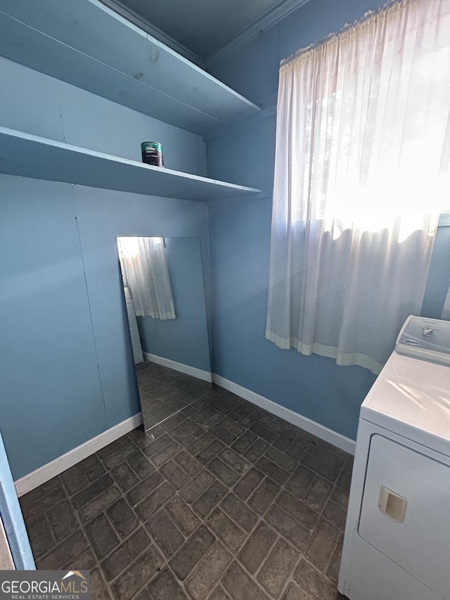 laundry area featuring laundry area, baseboards, brick patterned floor, and washer / dryer