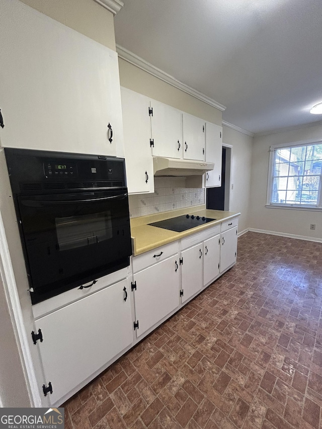 kitchen with under cabinet range hood, white cabinetry, ornamental molding, black appliances, and tasteful backsplash