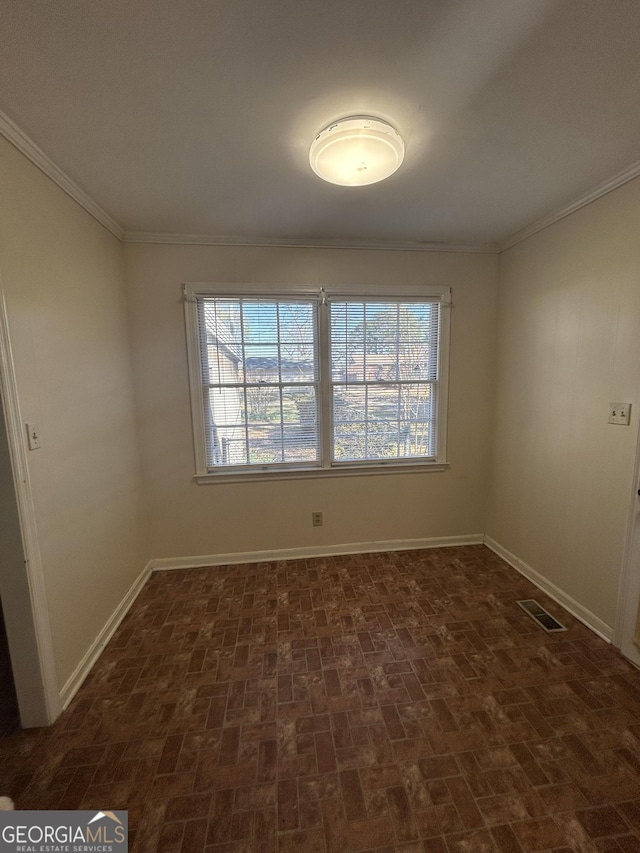 unfurnished room featuring brick floor, visible vents, baseboards, a wealth of natural light, and crown molding
