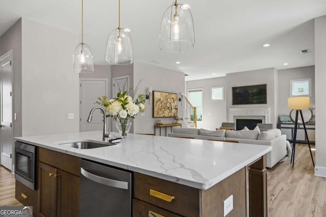 kitchen with dishwasher, light wood-type flooring, a fireplace, black microwave, and a sink