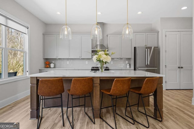 kitchen featuring a large island, light countertops, backsplash, and freestanding refrigerator