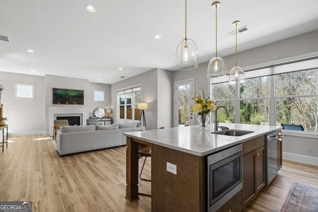 kitchen featuring visible vents, a premium fireplace, stainless steel appliances, a healthy amount of sunlight, and a sink