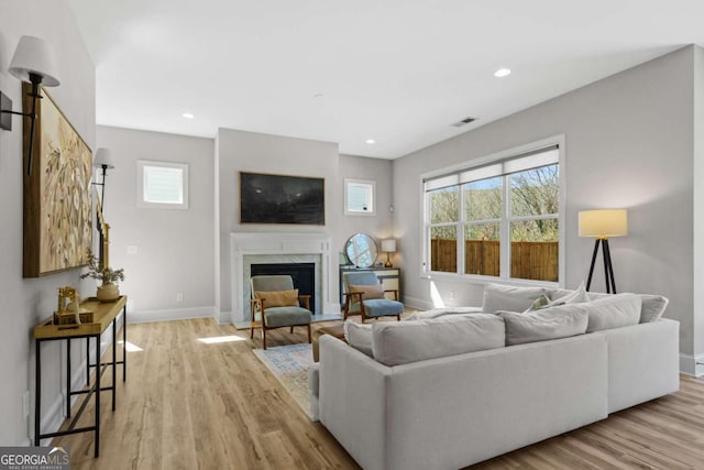 living room with recessed lighting, a fireplace, visible vents, baseboards, and light wood-style floors