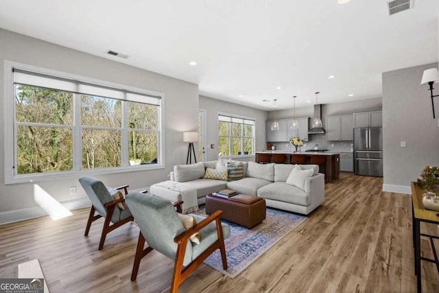 living room featuring light wood finished floors, recessed lighting, visible vents, and baseboards