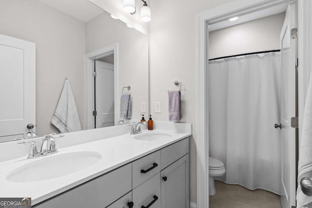 bathroom with double vanity, tile patterned flooring, toilet, and a sink