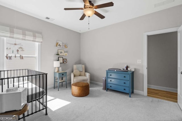 bedroom featuring carpet flooring, visible vents, a crib, and baseboards