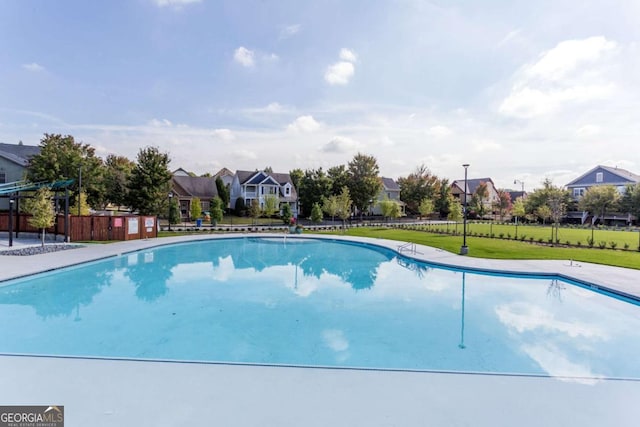 pool featuring a lawn, fence, and a residential view