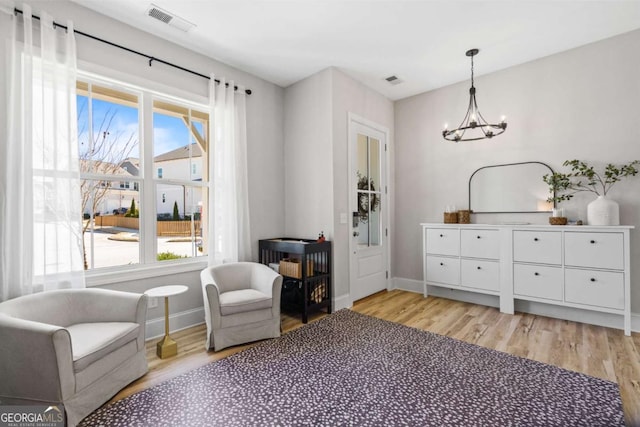 living area with light wood-style floors, visible vents, and plenty of natural light