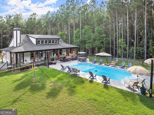 outdoor pool with a patio, fence, a gazebo, a lawn, and a forest view