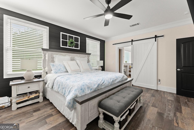 bedroom featuring a barn door, multiple windows, wood finished floors, and visible vents