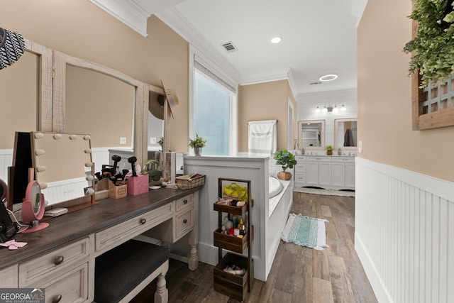 interior space featuring a wainscoted wall, wood finished floors, vanity, visible vents, and crown molding