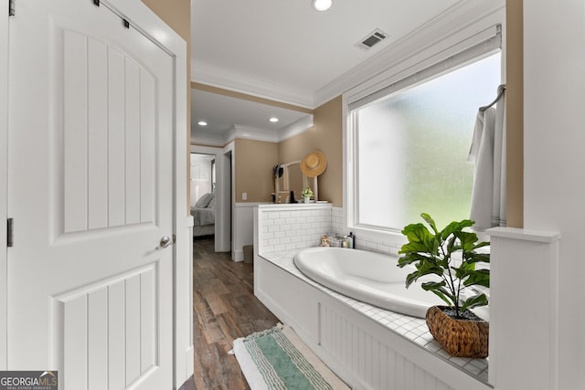 full bath with a garden tub, crown molding, recessed lighting, visible vents, and wood finished floors