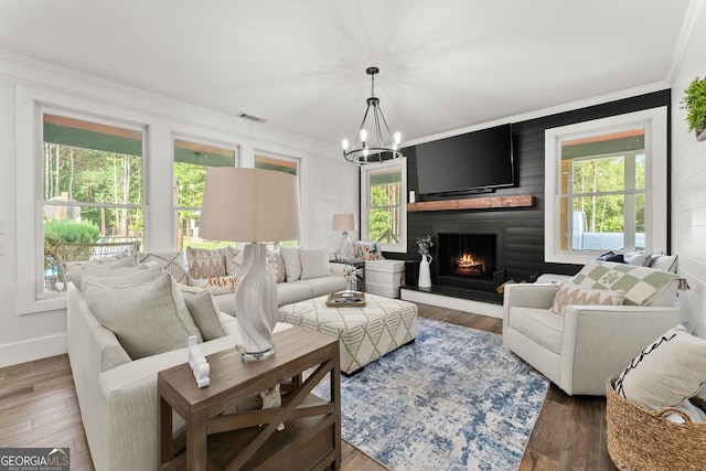 living area with a large fireplace, wood finished floors, visible vents, and crown molding