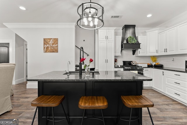 kitchen featuring premium range hood, a kitchen bar, a sink, and crown molding