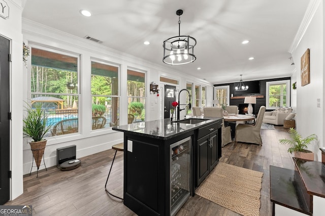 kitchen with beverage cooler, a sink, dark cabinetry, dark wood-style floors, and crown molding