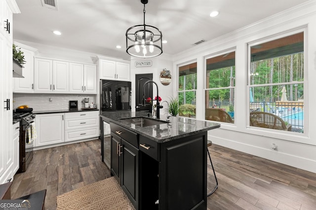 kitchen featuring a sink, white cabinetry, ornamental molding, dark cabinetry, and black gas range oven