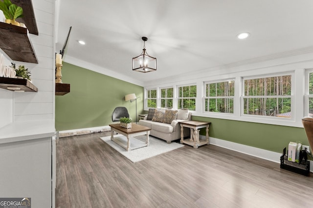 interior space with wood finished floors, baseboards, vaulted ceiling, ornamental molding, and an inviting chandelier