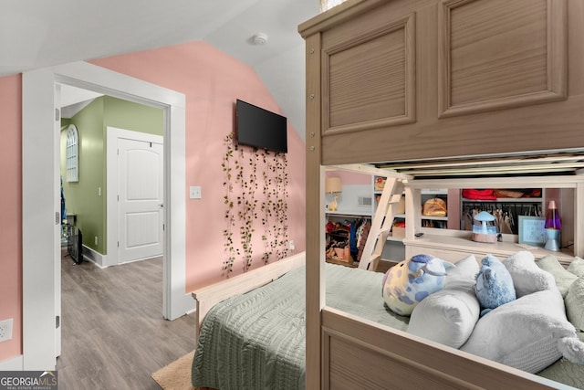 bedroom with lofted ceiling, wood finished floors, and baseboards