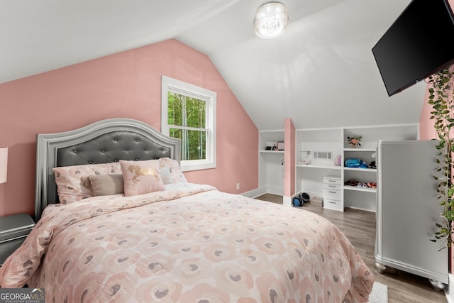 bedroom featuring lofted ceiling, baseboards, and wood finished floors