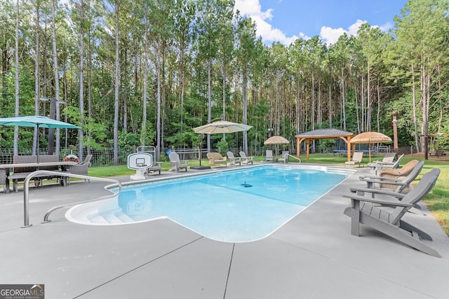 community pool with a patio area, fence, and a gazebo